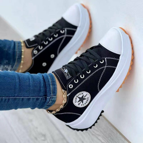 Black Converse sneakers with white soles worn by a person in blue jeans.